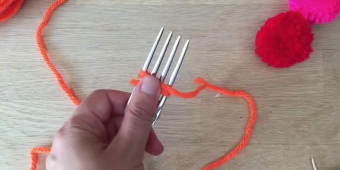 Cara membuat pompom: mulailah membungkus garpu dengan benang