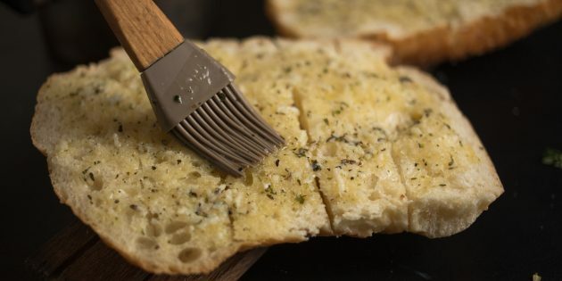 Cara membuat crouton keju bawang putih: olesi mentega ke seluruh permukaan roti