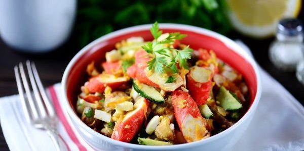 Salad dengan goreng kepiting tongkat, jamur, mentimun dan telur