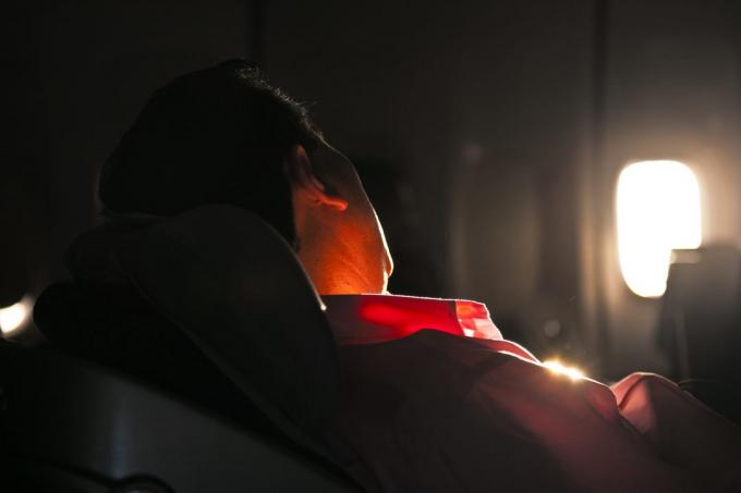 pria tidur di kursi pesawat terbang di sunrise