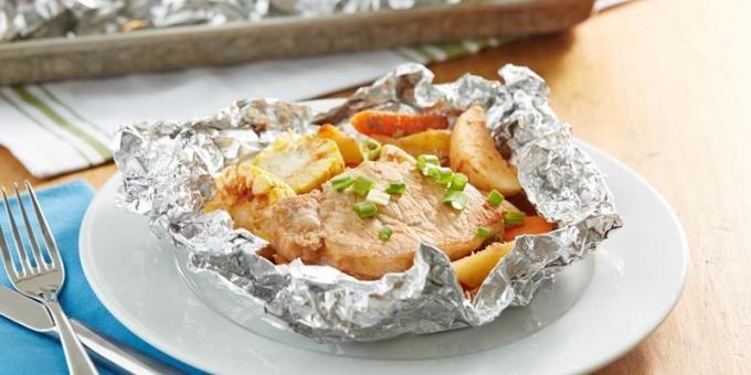 Babi dengan kentang dan jagung di foil dalam oven