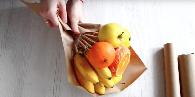 Masukan sekelompok buah dengan tangan Anda secara diagonal di kertas dan bungkus bagian bawah